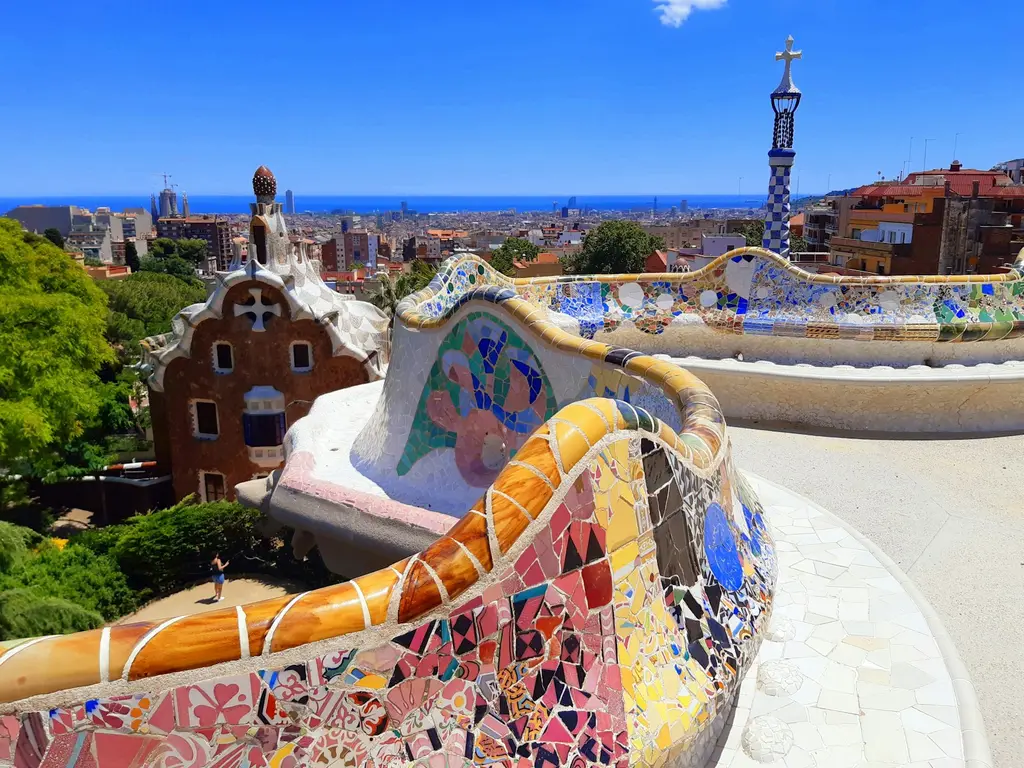 Barcelona: A view from the benches on a summer day at Park Güell in Barcelona, Spain The mosaic serpentine bench at Park Güell overlooking the city of Barcelona