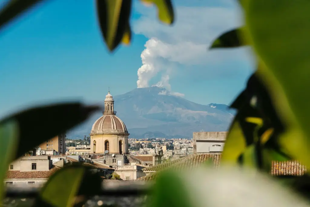 Catania: Etna - Duomo Catania - Sicilia a view of a city with a mountain in the background
