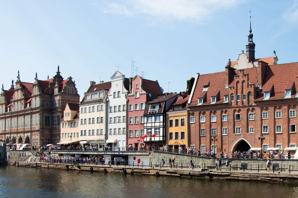 Gdańsk: Charming view of Gdańsk's historic waterfront lined with colorful buildings and lively visitors.