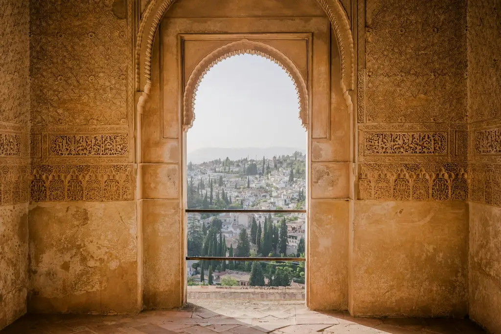 Granada: An arched stone doorway framing a view of the white buildings in Granada