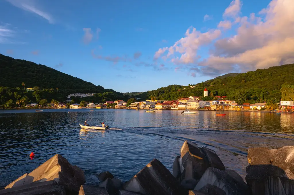 Guadeloupe: A picturesque sunset over Deshaies Bay, Guadeloupe, with a small boat in the foreground.