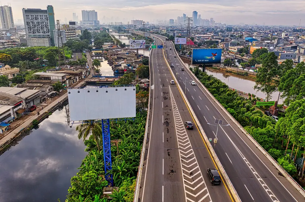 Jakarta: Dynamic aerial view of an expressway in Jakarta cityscape with skyline and river in sight.
