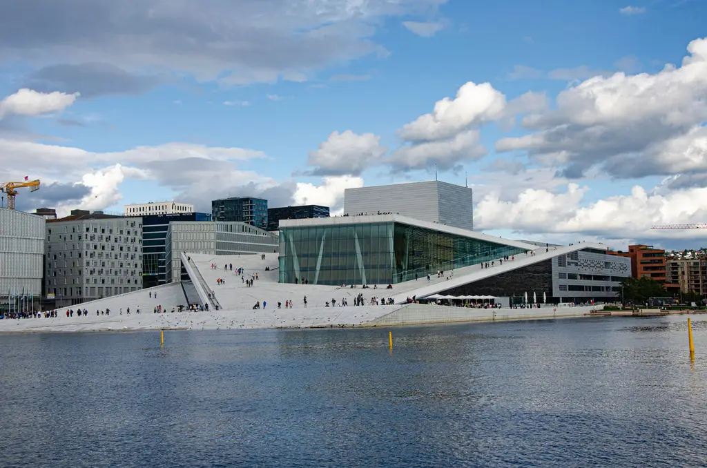 Oslo: Stunning view of the Oslo Opera House by the waterfront under a blue sky, showcasing modern architecture.