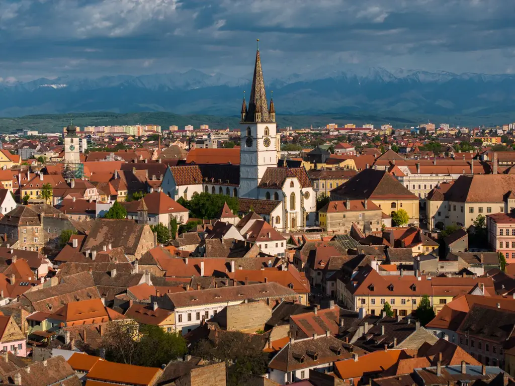 Sibiu: Aerial view of Sibiu, Romania showcasing historic architecture and mountainous backdrop.