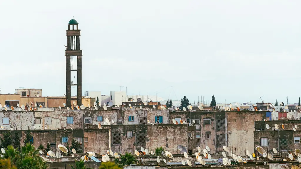 Tunis: Urban rooftops with satellite dishes beneath a towering minaret in Tunis, Tunisia.